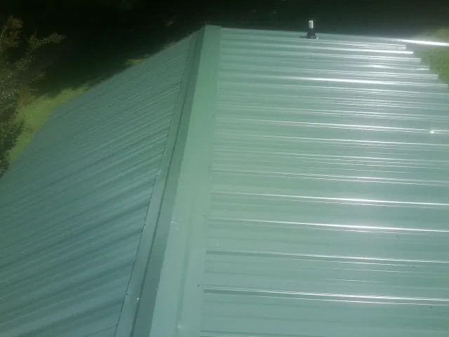 New green metal panels meeting at the ridge of a roof — Flat Roof Repair work by our crew in Beryl