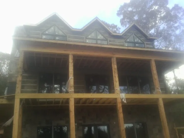 Dormers and porch framing on a large log home under construction — Roof Coating work by our crew in Beryl