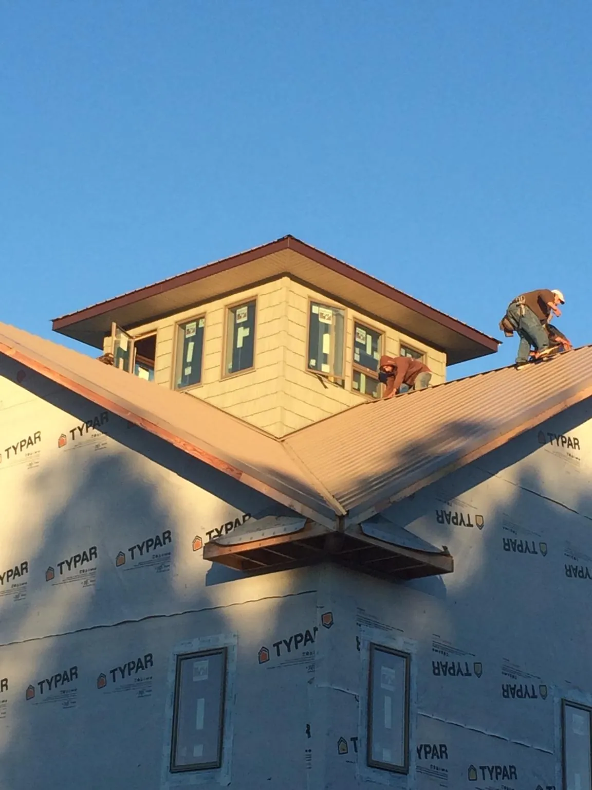 Roofers working around a rooftop cupola on a new metal roof at sunset — Roof Waterproofing in Beryl by Roofing Brothers